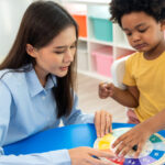 Profissional realizando uma avaliação neuropsicológica infantil com uma criança, utilizando lápis coloridos para atividades cognitivas.