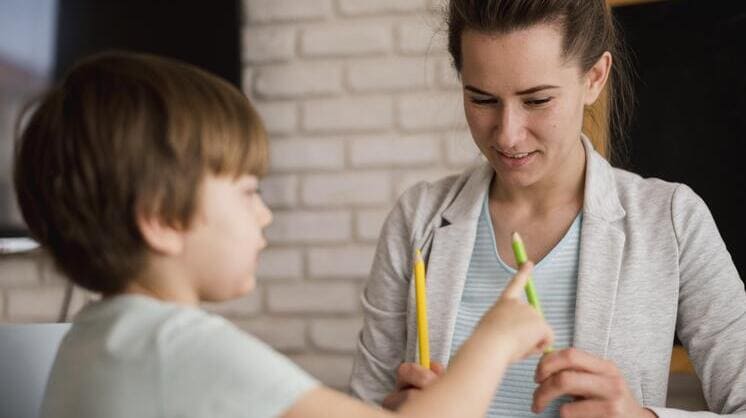 Profissional realizando uma avaliação neuropsicológica infantil com uma criança, utilizando lápis coloridos para atividades cognitivas.