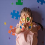 Criança segurando peças coloridas de quebra-cabeça nas mãos, representando o cuidado e o acolhimento no desenvolvimento infantil e no autismo.