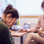 Profissional acolhe trabalhadora abalada no escritório sobre saúde mental no trabalho.