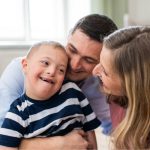 Pais abraçam e sorriem com o filho para representar a família na terapia ABA.