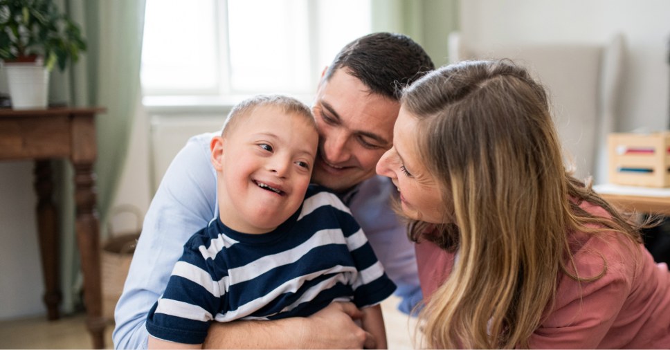 Pais abraçam e sorriem com o filho para representar a família na terapia ABA.
