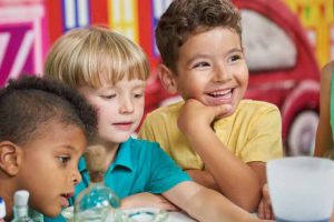 Dinâmicas coletivas e habilidades sociais no TEA Grupo de crianças sorrindo em atividades lúdicas, exemplificando as habilidades sociais no TEA.